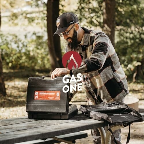 Man setting up Gas One stove on outdoor picnic table.